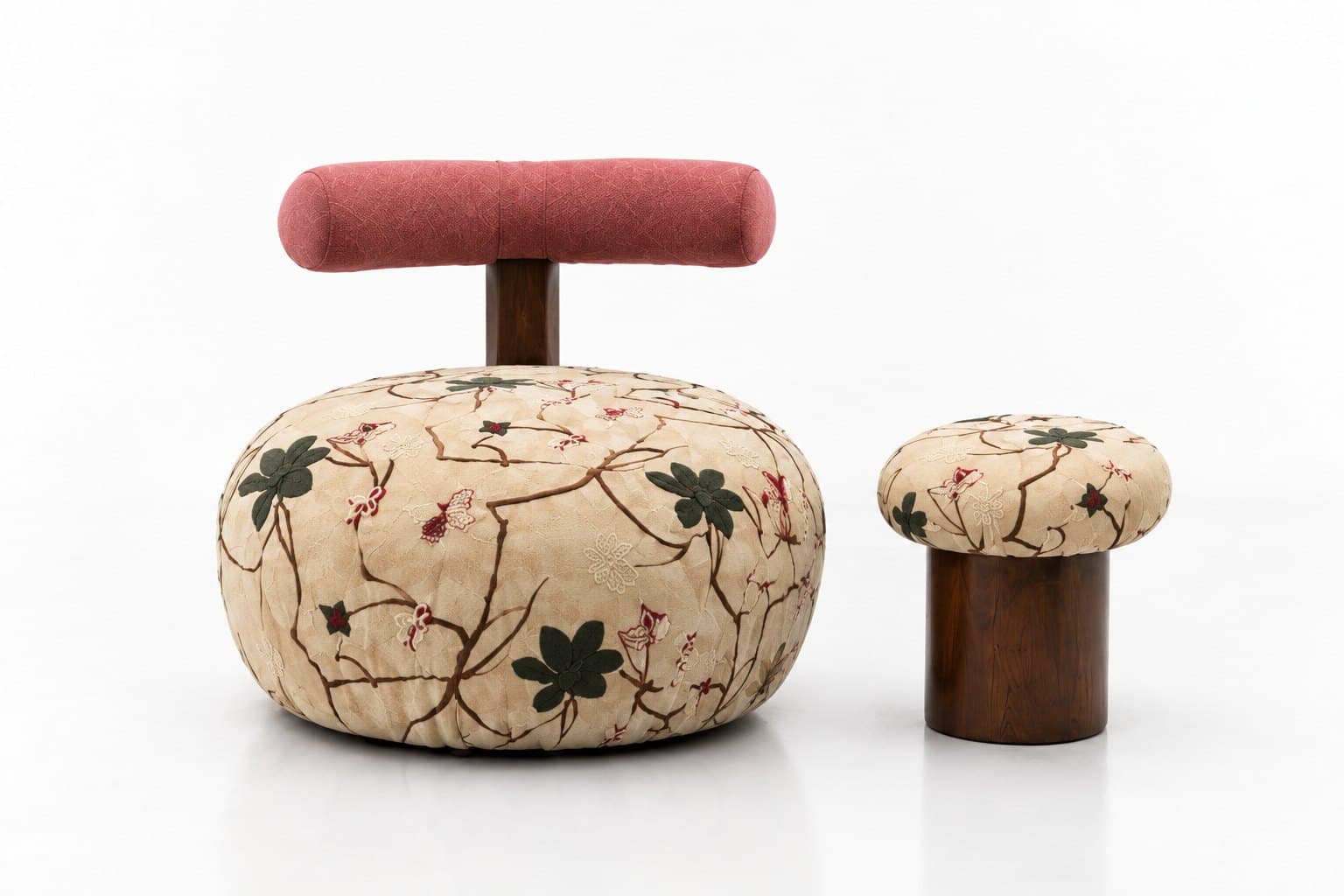The embroidered chair and stool seen from three-quarters, showing the rounded form of the seat